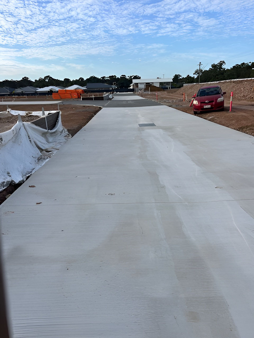 Long freshly finished concrete pavement beside new house sites, tall view