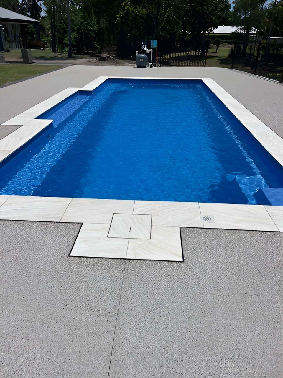 Rectangular pool with pale coping and an exposed aggregate surround, tall view