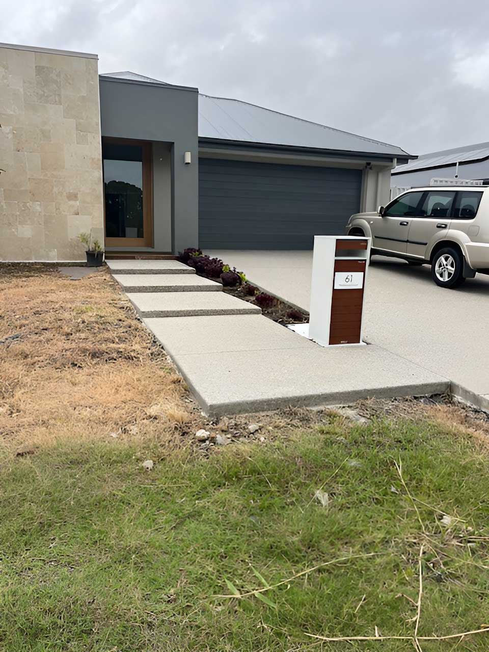 Concrete path slabs leading to a new home's front door beside the driveway