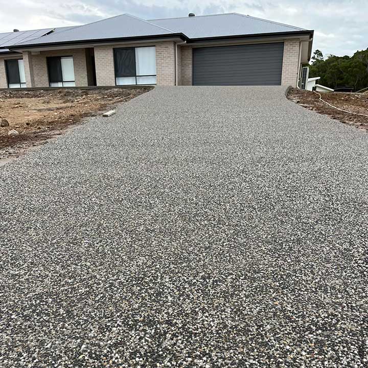 Long exposed aggregate driveway leading to a new brick home