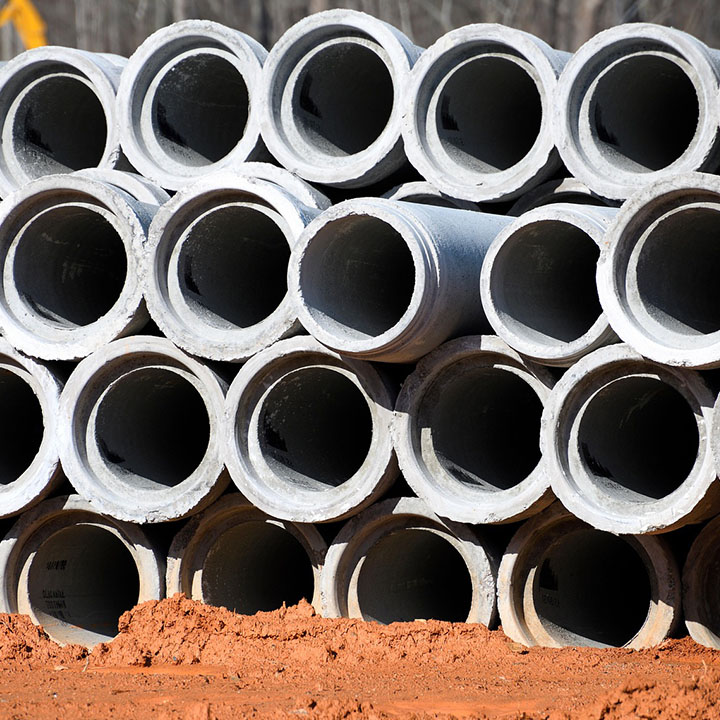 Stack of round concrete pipes on red soil