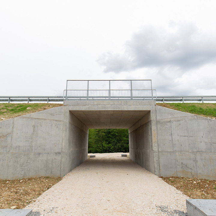 Concrete box culvert underpass with a gravel path running through it