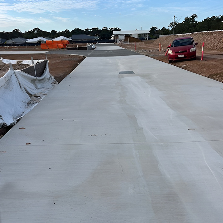 Long freshly finished concrete pavement beside new house sites